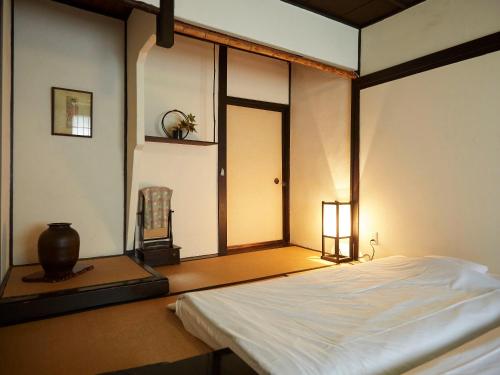 a bedroom with a white bed with a window at Takeyaso Ryokan in Amagasaki