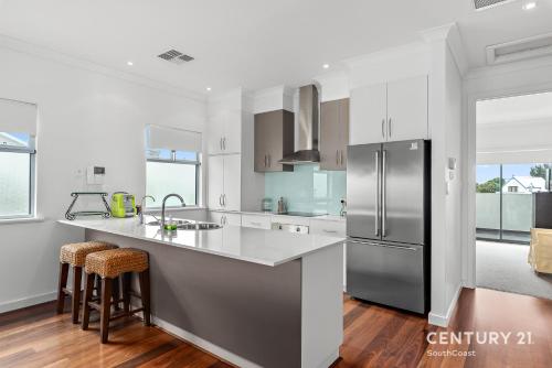 a kitchen with white cabinets and a stainless steel refrigerator at Percival Point - Port Willunga - C21 SouthCoast Holidays in Port Willunga