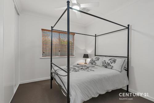 a bedroom with a black canopy bed in a white room at Percival Point - Port Willunga - C21 SouthCoast Holidays in Port Willunga