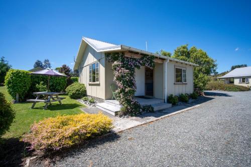 a small house with a picnic table in the yard at Blue Thistle Cottages in Te Anau