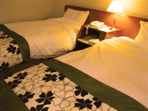 a hotel room with two beds and a phone at Matsunoyu in Matsue