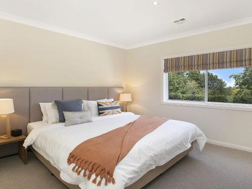 a bedroom with a large bed and a window at Hillview Cottage in Bowral
