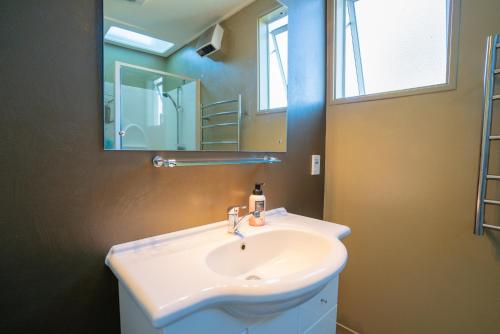 een badkamer met een witte wastafel en een spiegel bij Dee's on Bligh - Te Anau Holiday Home in Te Anau