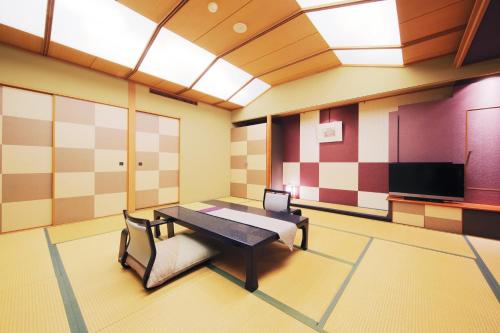 a room with a table and a couch and a tv at Matsunoyu in Matsue