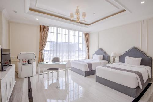 a hotel room with two beds and a kitchen at Grand Senyum Hotel, Tugu Yogyakarta in Yogyakarta