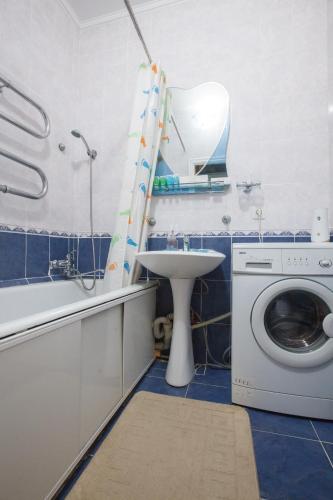 uma casa de banho com uma máquina de lavar roupa e um lavatório em Квартира на Пушкина em Almaty