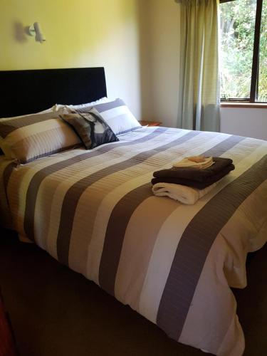 a bedroom with a large bed with a striped blanket at Awesome View Cottage in Great Barrier Island
