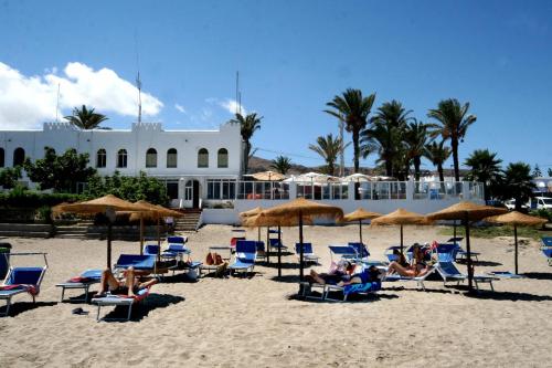 a group of people sitting in chairs and umbrellas on a beach at Hotel Playa in Mojácar