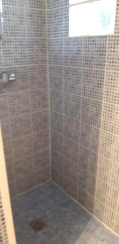 La salle de bains est pourvue d'une douche et de murs carrelés. dans l'établissement studio de jack, à Le Mesnil-Esnard