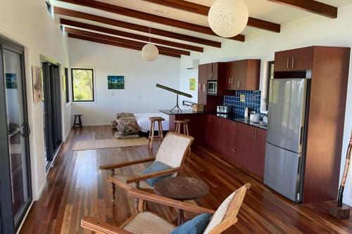 uma cozinha com pisos em madeira e uma cozinha com um frigorífico em Ridge Cabin - Stunning Views - 5km From Neighbours em Airlie Beach