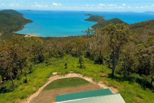 an aerial view of a golf course with the ocean in the background at Ridge Cabin - Stunning Views - 5km From Neighbours in Airlie Beach