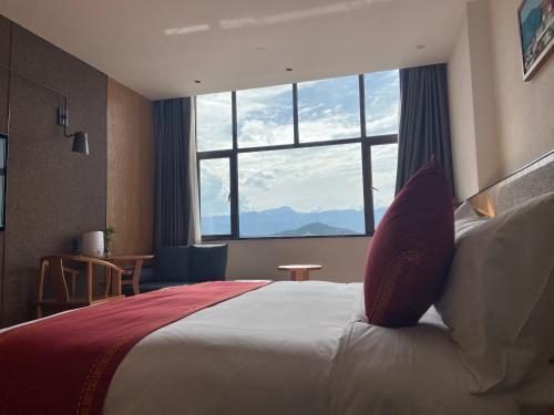a hotel room with a large bed with a large window at Ramada by Wyndham Diqing in Shangri-La