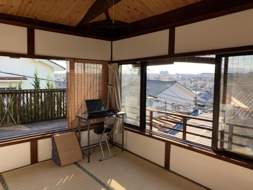 a room with a desk and a laptop on a balcony at Munetada House in Kyoto