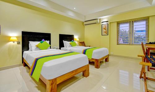 two beds in a room with yellow walls at Treebo Vapr Guindy Ekkatuthangal in Chennai