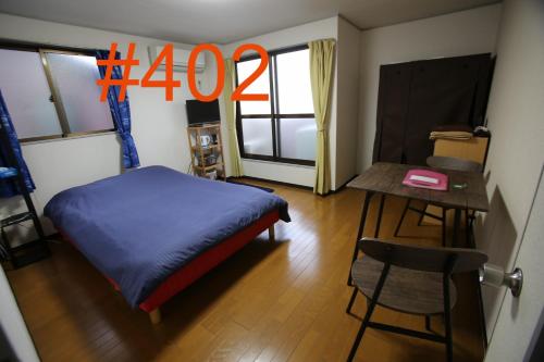 a room with a bed and a table and a desk at マンションロアジス 大阪市東淀川区相川 in Osaka