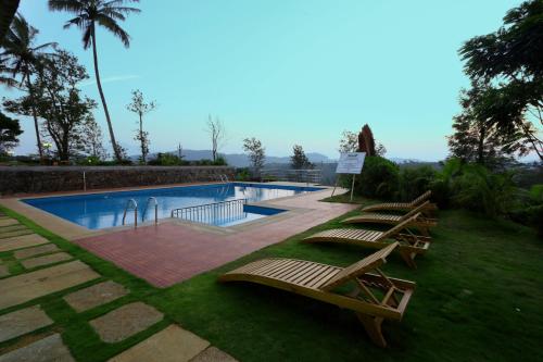 een zwembad met drie lounges en een rij stoelen bij Parisons Plantation Experiences by Abad in Mananthavady