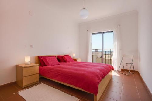 een slaapkamer met een groot rood bed en een raam bij Meia Praia Beach Apartment in Lagos