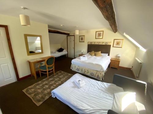 a hotel room with two beds and a desk at The Royal Oak in Ashbourne