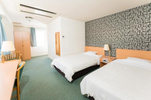 ein Hotelzimmer mit 2 Betten und einer Wand in der Unterkunft Hotel Ark 21 in Kurayoshi