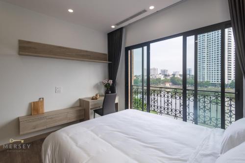 um quarto com uma grande cama branca e uma varanda em Mersey Central Hanoi Apart'Hotel em Hanói