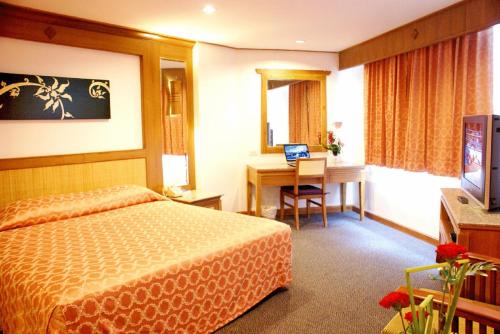 ein Hotelzimmer mit einem Bett und einem Schreibtisch in der Unterkunft Royal Twins Palace Hotel in Pattaya