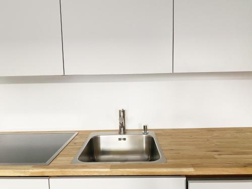 a stainless steel sink in a kitchen with white cabinets at Haus Münsterblick in Reichenau