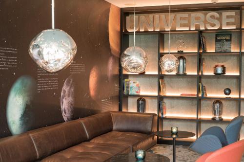 a living room with a couch and a book shelf at Motel One Berlin-Tiergarten in Berlin