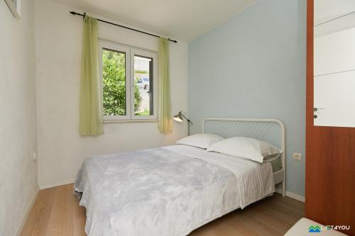 a white bedroom with a bed and a window at Mljet 2 You - seafront apartment 2+2 in Sobra