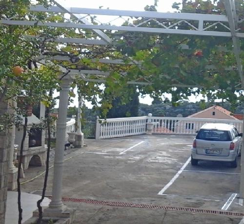 un coche aparcado en un estacionamiento con una valla blanca en Apartments and Room Katja, en Mlini