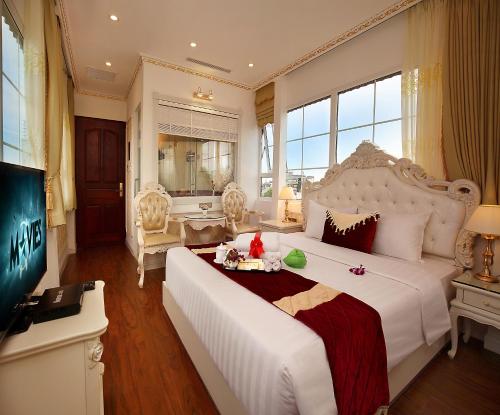 a bedroom with a large white bed and a television at Hanoi Hotel Royal in Hanoi
