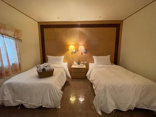 two beds in a hotel room with white sheets at Shexia Liyu Hot Spring in Checheng