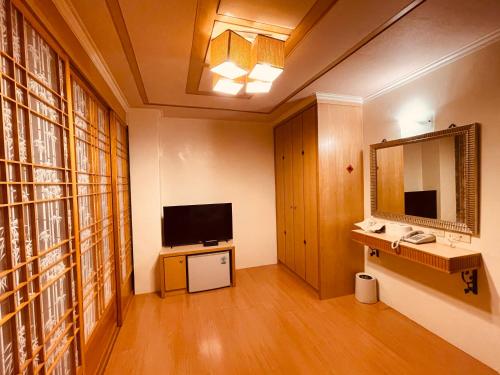 a living room with a television and a mirror at Shexia Liyu Hot Spring in Checheng