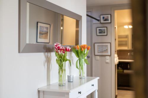deux vases avec des fleurs sur une table devant un miroir dans l'établissement 