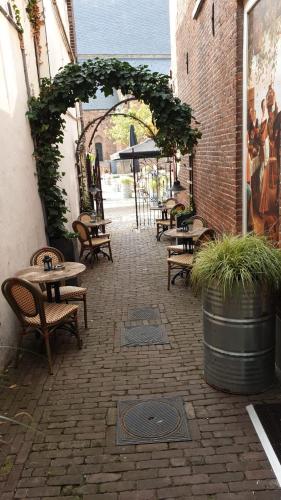 an outdoor patio with tables and chairs and an arch at BijHillen in bed in Winterswijk