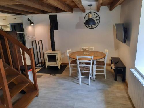 a dining room with a table and chairs and a clock at Gîte du Petit Moulin in Réaumur