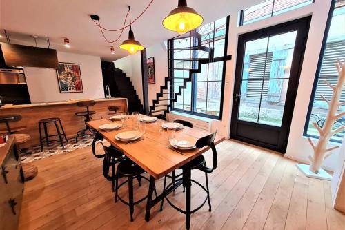 a dining room with a wooden table and some windows at L'ATELIER DU CHAPEAU ROUGE EN PLEIN CENTRE VILLE in Dijon