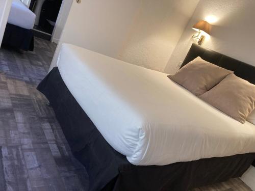 a large white bed with a black headboard in a room at Hotel De La Mer in Le Barcarès