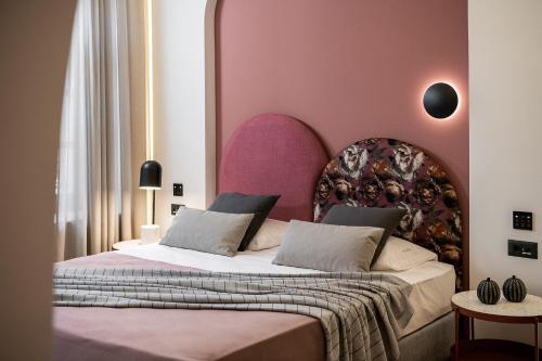a bedroom with a large bed with a pink headboard at Malmo Historic Hotel in Chania Town