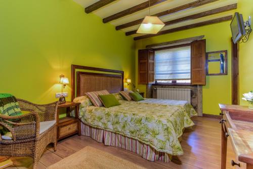a bedroom with green walls and a bed and a chair at Casal dos Celenis in Caldas de Reis