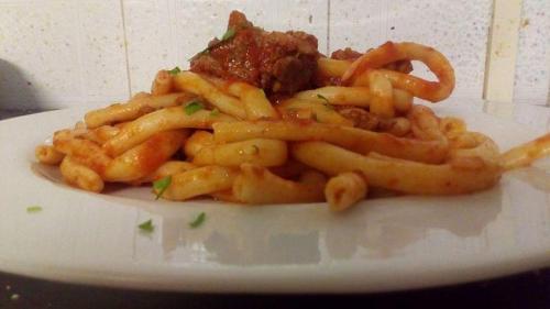 a plate of pasta with meat and onion rings at B&B Ristorante Grotta Del Romito in Papasidero