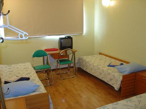 a room with two beds and a desk and a tv at Kuressaare Airport Guest House in Kuressaare
