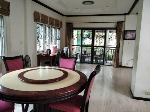 a dining room with a table and chairs and windows at Pool Villa Armthong Home in Ban Nong Toei