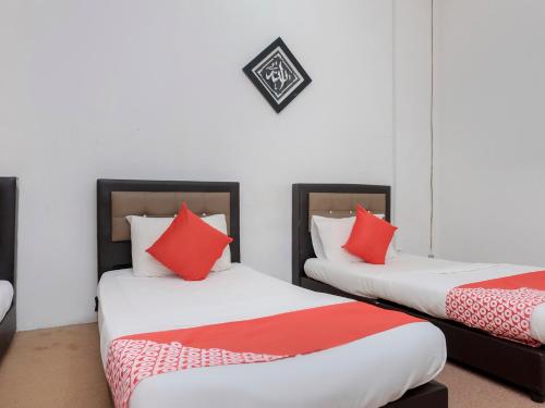 2 camas en una habitación con almohadas rojas y blancas en OYO 90180 Gemilang Hotel Kerteh, en Dungun