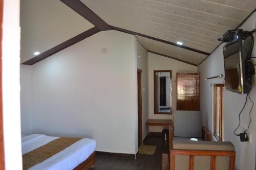 a bedroom with a bed and a chair in a room at The Hillans Resort & Cottages in Kanatal