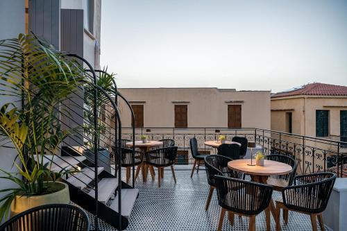 a patio with tables and chairs on a balcony at Malmo Historic Hotel in Chania Town