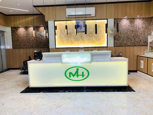 a lobby with a counter with the mh logo on it at Mithilesh Hotel in Kaithal