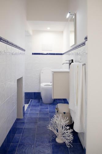 a bathroom with a toilet and a blue tile floor at BLU MARE suite privata & apartment in Terrasini
