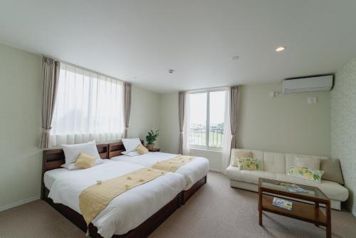um quarto de hotel com duas camas e um sofá em Ecot Shimozato 2 em Ilhas Miyako