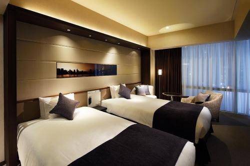 ein Hotelzimmer mit 2 Betten und einem Stuhl in der Unterkunft Solaria Nishitetsu Hotel Ginza in Tokio