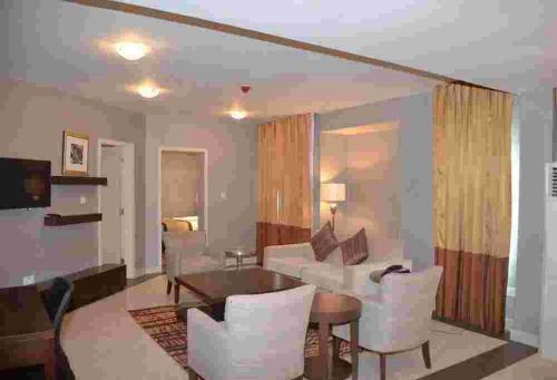 a living room with a couch and a table and chairs at De Brass Suites Hotel - Deluxe in Yenagoa